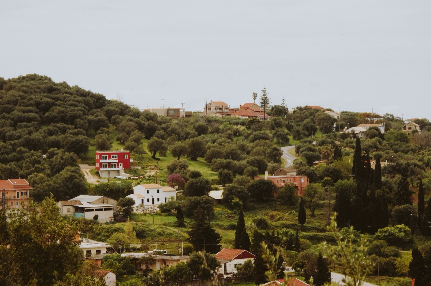 A hillside village of homes nestled among green trees and countryside.